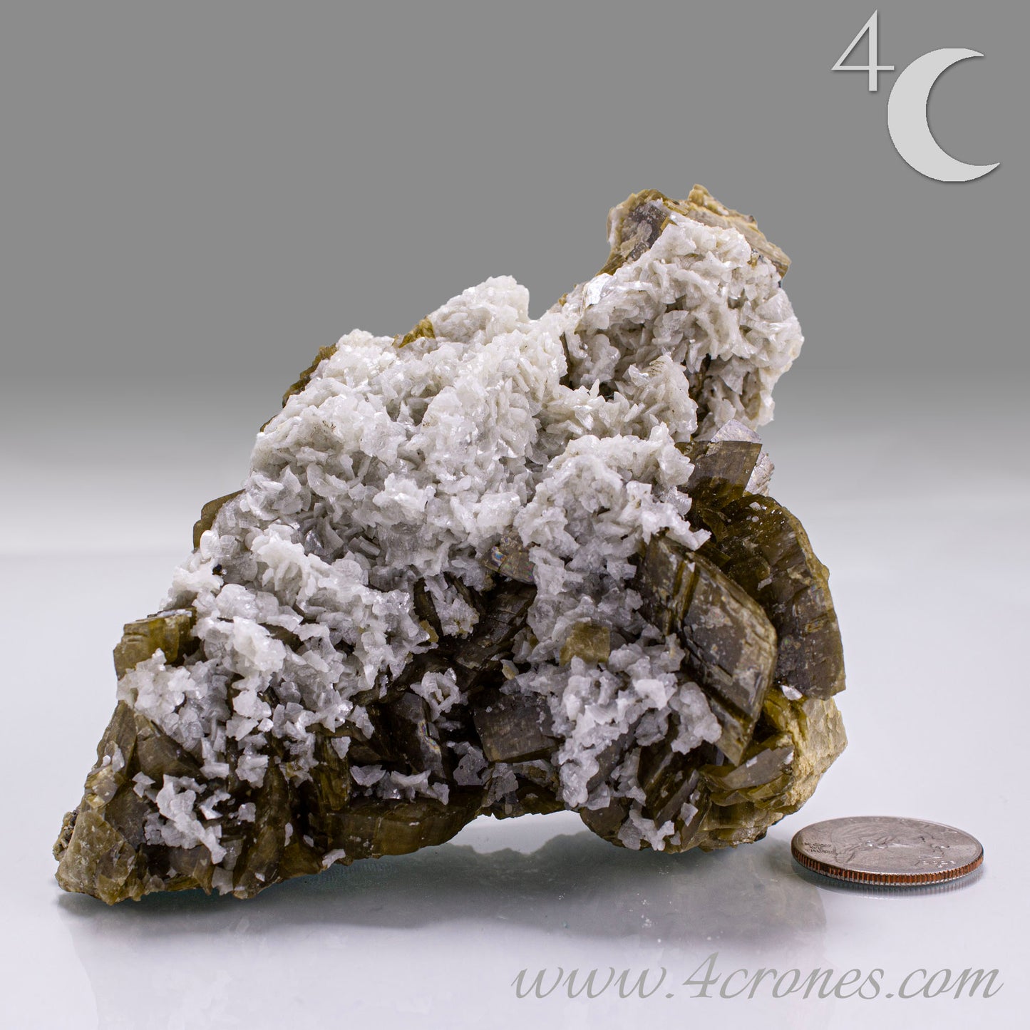 Mineral specimen with white crystals on a gray background, featuring the brand '4 Crones'.