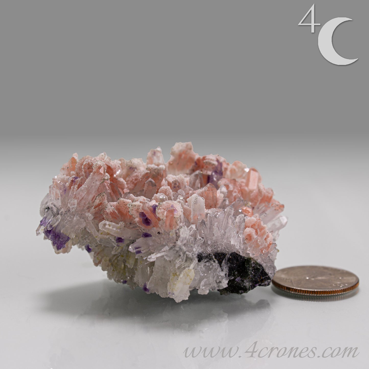 A delicate and visually dramatic specimen, this piece features pale pink Rhodochrosite dispersed among fine, radiating Quartz needles, with subtle inclusions of deep purple Fluorite.