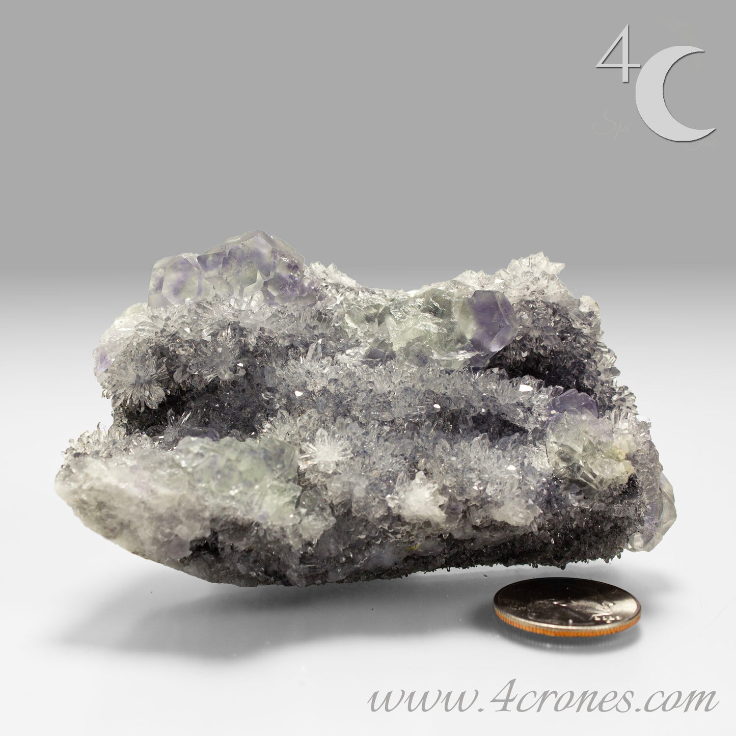 These beautiful green fluorites have enchanting delicate blue-purple phantoms. They are nestled in a dazzling bed of sparkling needle quartz and their subtlety and color shifts under various light sources create the feeling of being on a treasure hunt. Suddenly, another purple-blue phantom fluorite crystal appears amidst the crystal-clear twinkling needle quartz points. To top it off these amazing specimens glow and fluoresce a deep Lavendar under UV light. www.4crones.com