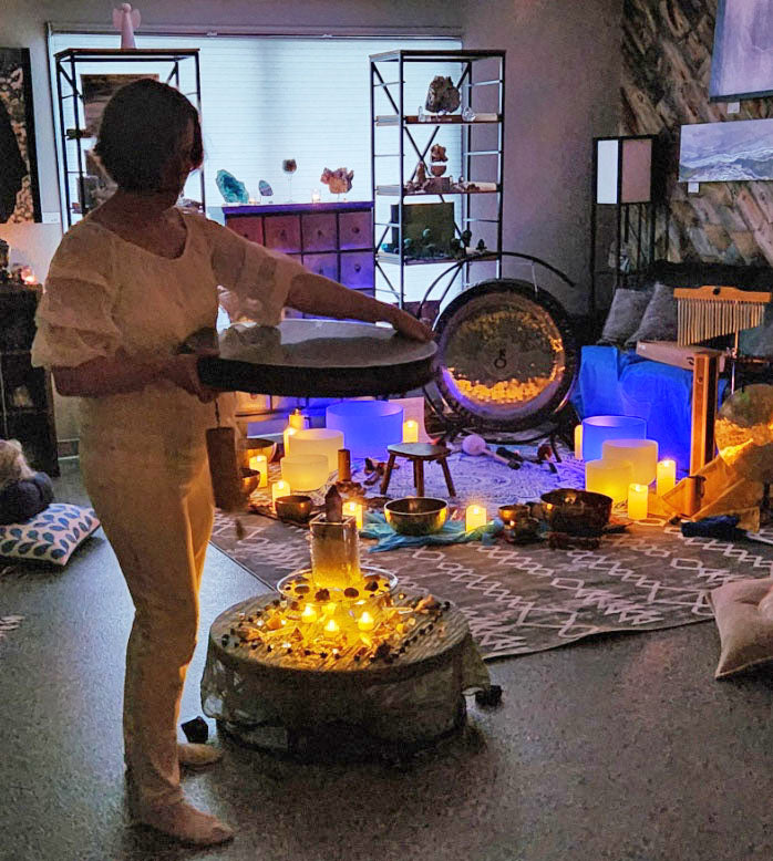 Annmarie Fore holding ocean drum in a room with candles doing a sound bath at 4 crones