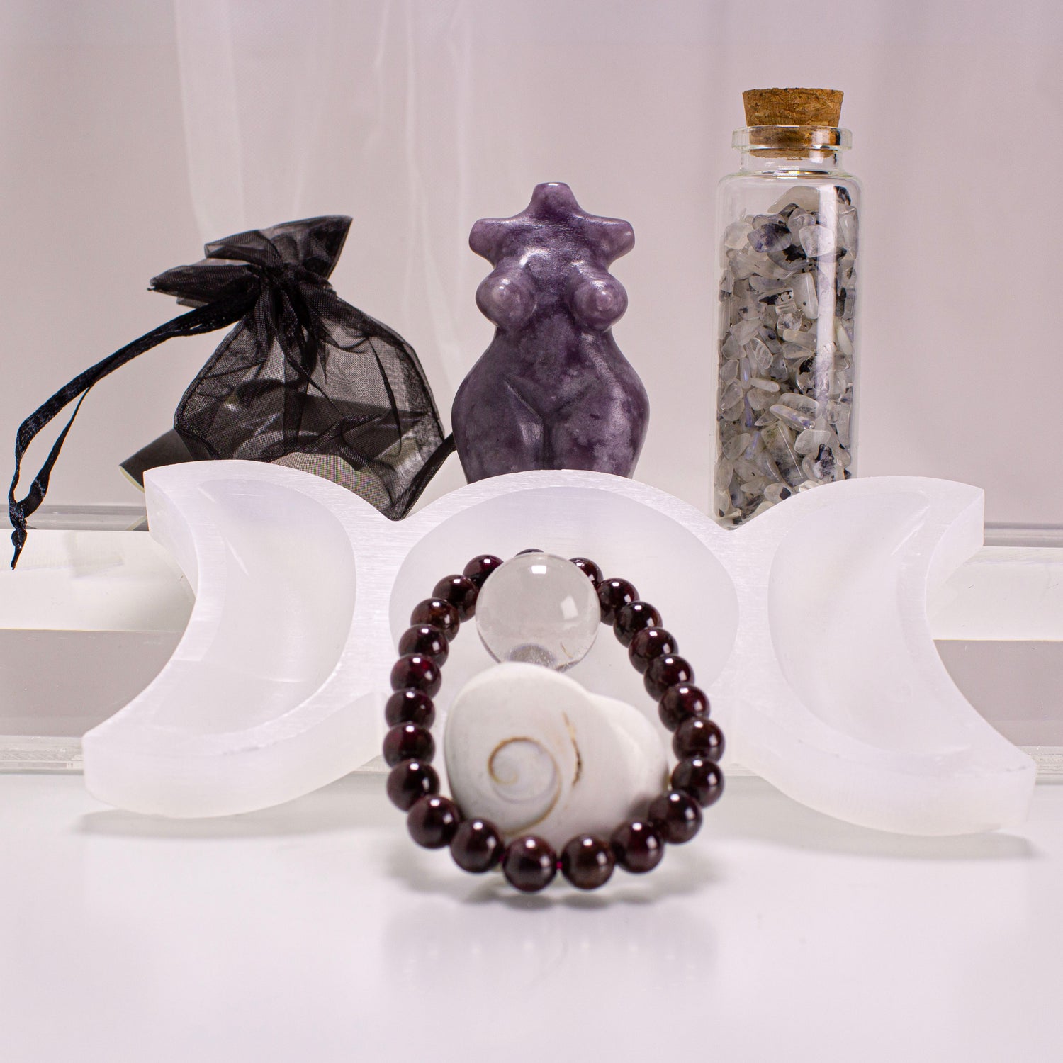 Decorative items including a bracelet, star-shaped object, and bottle with stones on a white surface.