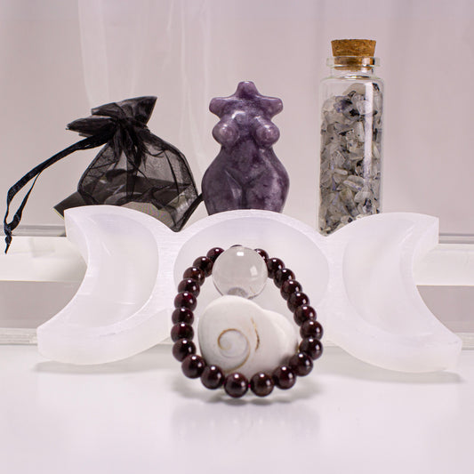 Decorative items including a bracelet, star-shaped object, and bottle with stones on a white surface.
